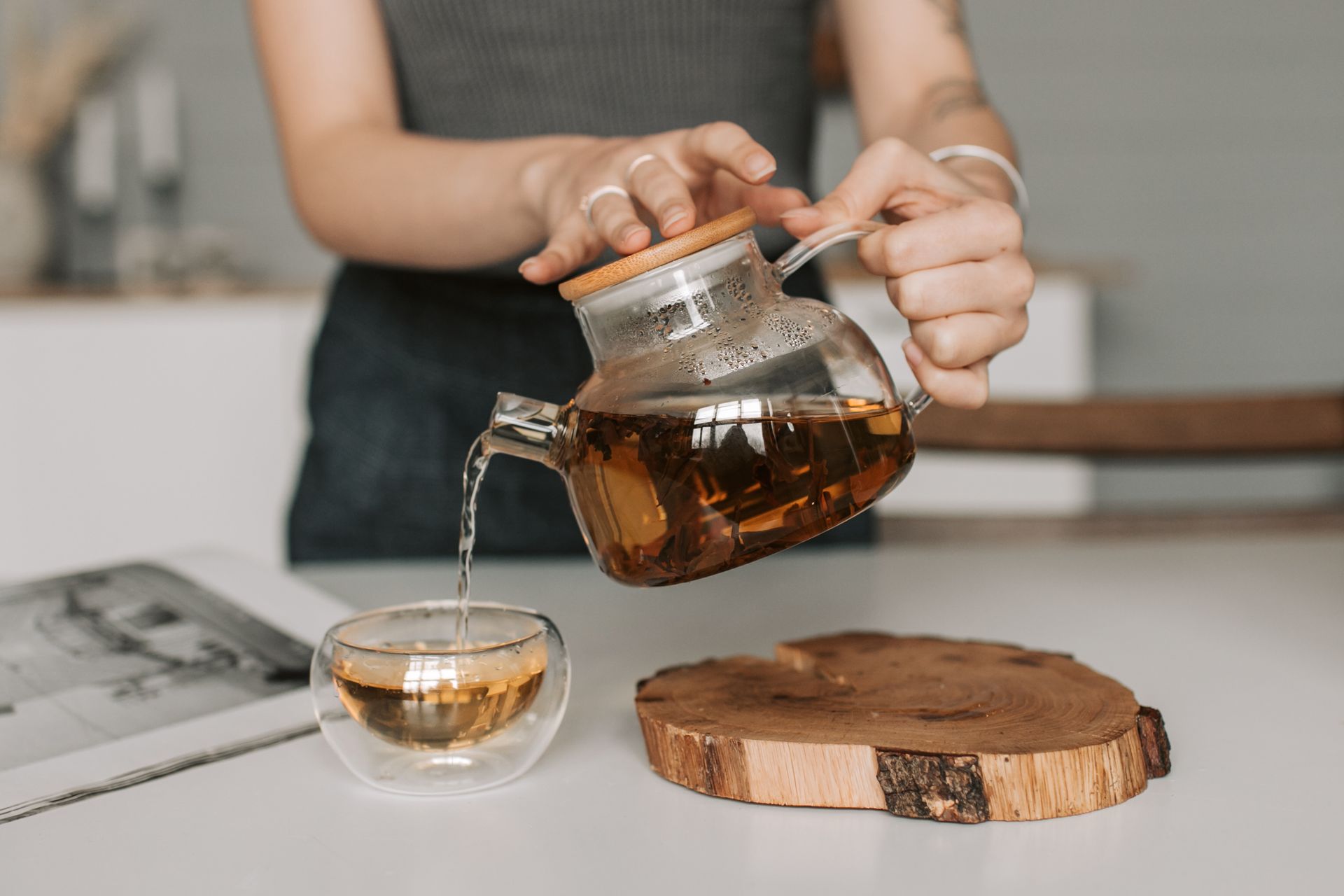 Tea being poured from a glass teapot into a glass cup