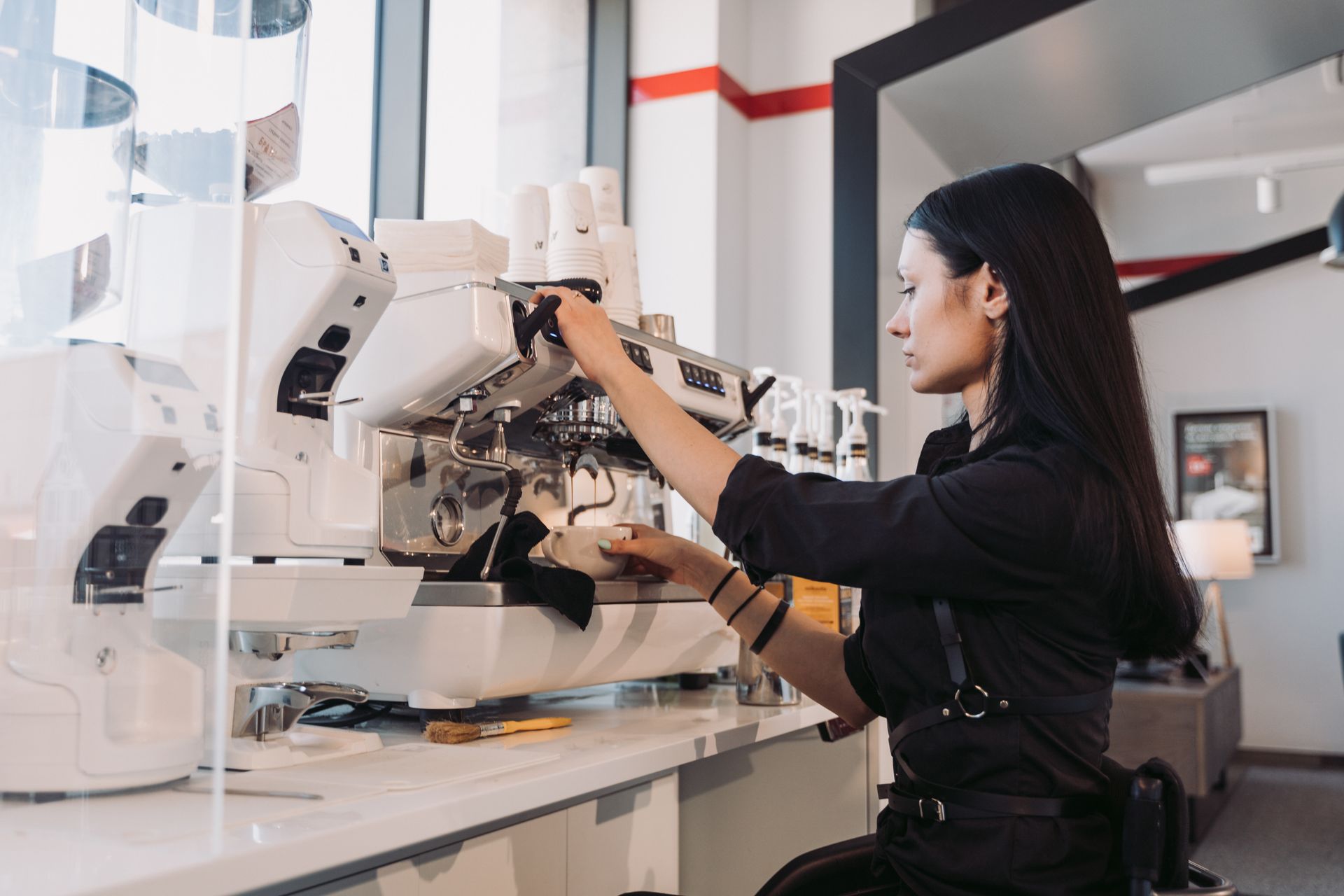 A barista pulling a shot at a white espresso machine